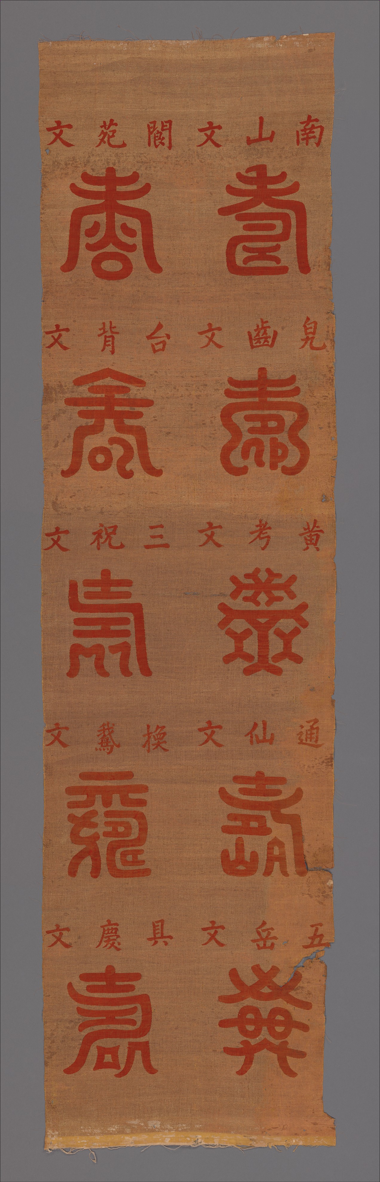 Ten red variant forms of the shou longevity character with smaller source inscriptions on a nineteenth-century tapestry panel
